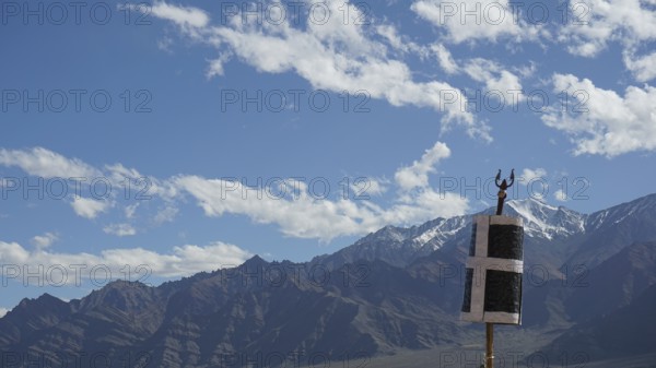 Mountain landscape with blue sky and clouds, flag in the foreground, trekking in Ladakh, Himalayas, India