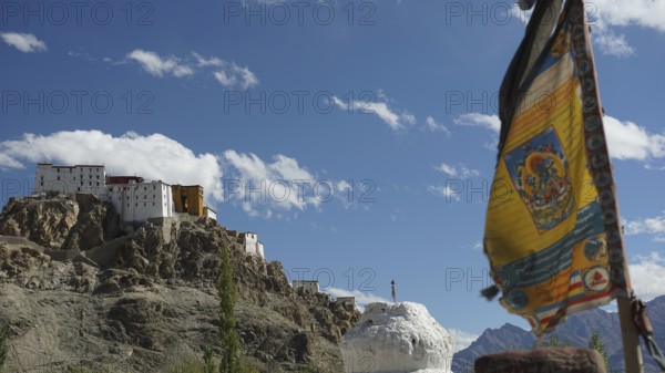 A Buddhist monastery on a hill with a fluttering prayer flag and majestic mountain views, trekking in Ladakh, Himalayas, India