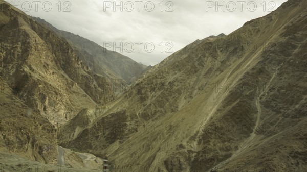 Wide, rocky mountains and a deep gorge under a cloudy sky, trekking in Ladakh, Himalayas, India