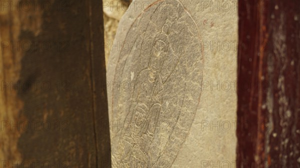 A stone slab with carved Buddha relief as a sacred work of art, trekking in Ladakh, Himalayas, India