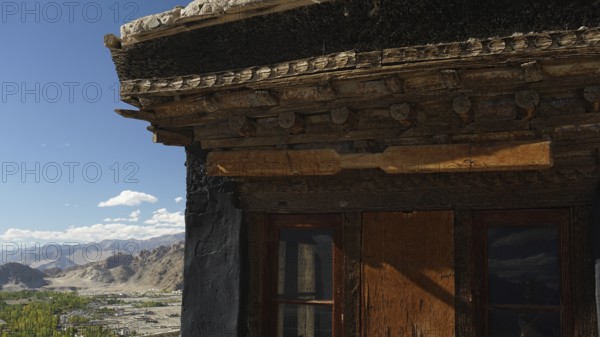 Detail of a wooden roof structure with window and mountain landscape in the background, trekking in Ladakh, Himalayas, India