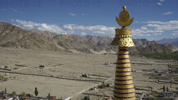 Golden stupa over a vast, mountainous landscape under a glowing sky, trekking in Ladakh, Himalayas, India