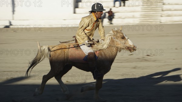 Single rider on horseback playing polo in traditional clothing on a horse moving, trekking in Ladakh, Himalayas, India