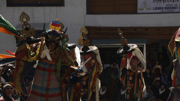 Several masked figures in colorful clothes perform a dance during a festival in Leh, trekking in Ladakh, Himalayas, India