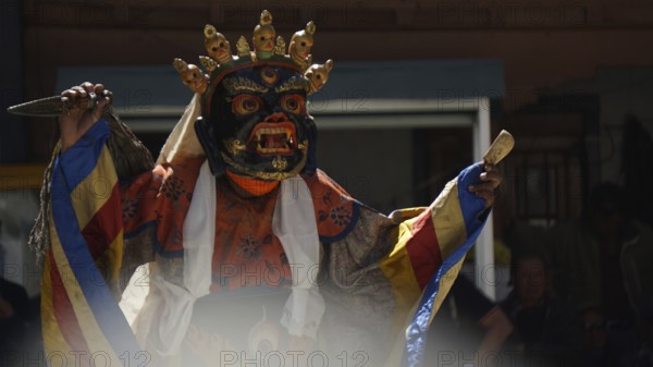 A mystical, colorfully dressed dancer wears a decorative mask during a ritual, Leh, trekking in Ladakh, Himalayas, India