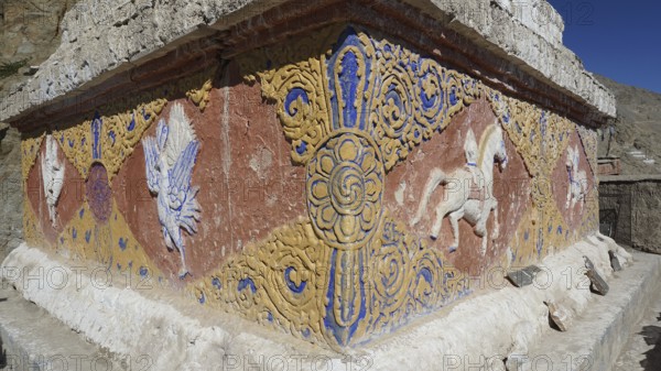 An artfully decorated relief with colorful patterns and symbols on a stone wall, Leh, trekking in Ladakh, Himalayas, India