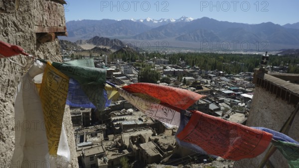 Colorful prayer flags fly over Leh with a mountainous landscape in the background, trekking in Ladakh, Himalayas, India