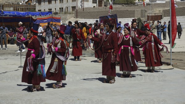 People wearing traditional clothes perform a dance surrounded by spectators at a festival in Leh, trekking in Ladakh, Himalayas, India