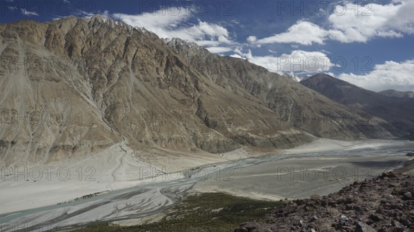 Mountain valley with river course between majestic mountain ranges under a lively sky, trekking in Ladakh, Himalayas, India