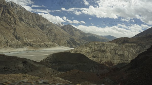 Wide mountain landscape under a cloudy sky with rocky slopes and a valley, trekking in Ladakh, Himalayas, India