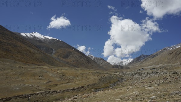 Extensive valley with meadows under a clear blue sky and white clouds, trekking in Ladakh, Himalayas, India