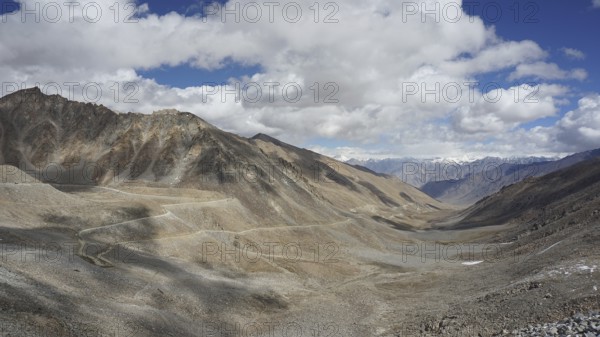 Wide mountain landscape with winding mountain road under a cloudy sky, trekking in Ladakh, Himalayas, India