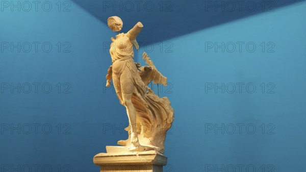 The Nike of Paionios, statue of the goddess of victory Nike from Parisian marble, fragment of an ancient female marble statue in dynamic pose against a blue background, Olympia Archaeological Museum, Ancient Olympia, Olympia, Peloponnese, Greece