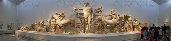 West pediment of the Temple of Zeus, Centauromachy, Kmapf between Centaurs and Lepiths, panoramic view of a group of ancient sculptures in the museum with visitors, Olympia Archaeological Museum, Ancient Olympia, Olympia, Peloponnese, Greece