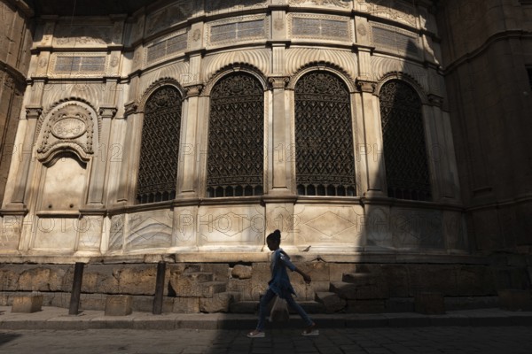 Cairo, Egypt. July 7th 2024 A young Egyptian girl walks past one of the many restored monuments along Sharia Al Muizz Li Din Allah near Khan El Khalili Bazaar, historical Cairo, Egypt