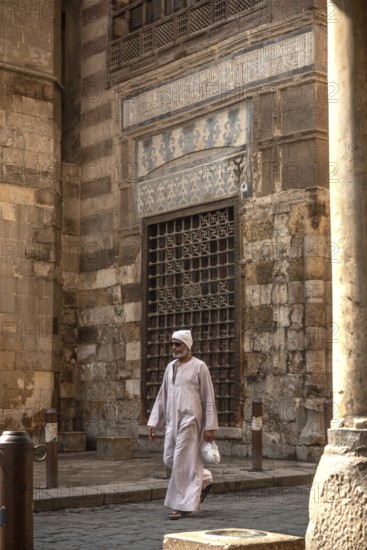 Cairo, Egypt. July 7th 2024 An Egyptian man wearing traditional clothes walks along the cobbled streets of Islamic Cairo, a historical district and UNESCO world heritage site, Cairo, Egypt