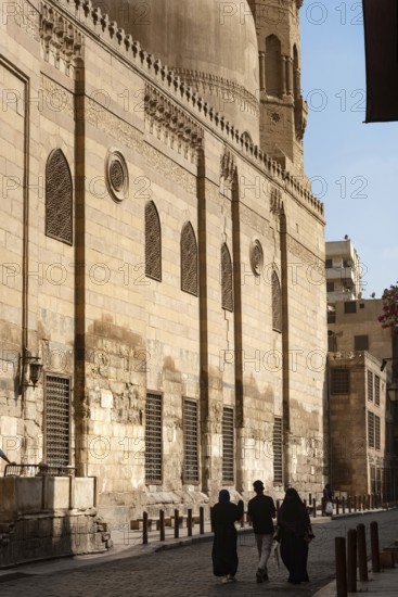 Local tourists walk past one of the many restored monuments along Sharia Al Muizz Li Din Allah near Khan El Khalili Bazaar, historical Cairo, Egypt