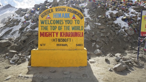 Welcome sign at Khardungla Pass surrounded by rocks and snow, trekking in Ladakh, Himalayas, India