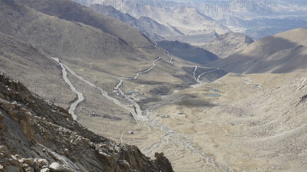 Serpentine road snakes through barren valleys and mountains, on the way to Nubra Valley, trekking in Ladakh, Himalayas, India