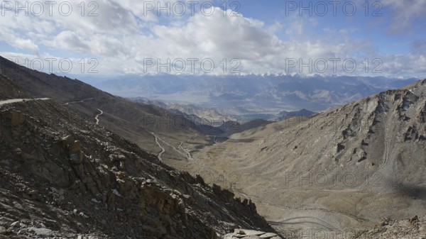 Barren mountain panorama with winding roads under a cloudy sky, trekking in Ladakh, Himalayas, India