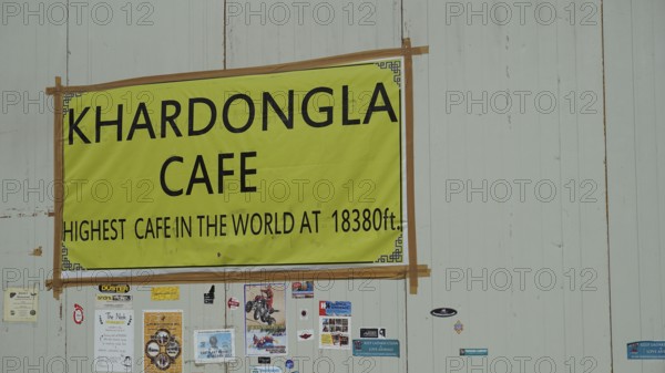Sign of a cafe at Khardungla Pass on a high mountain road with various stickers, trekking in Ladakh, Himalayas, India