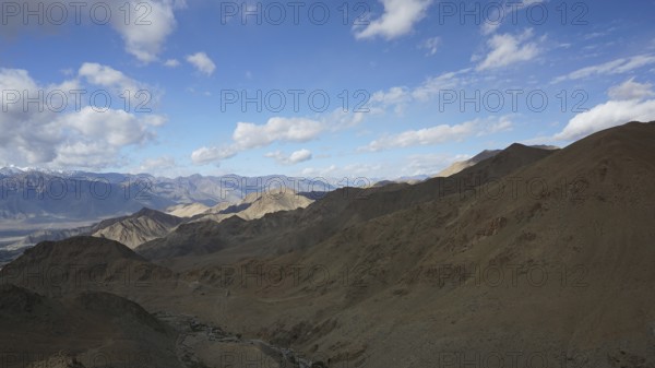Rugged mountain landscape under a blue sky with scattered clouds, trekking in Ladakh, Himalayas, India