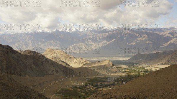Mountain landscape with cloudy sky, snowy peaks in the background, trekking in Ladakh, Himalayas, India