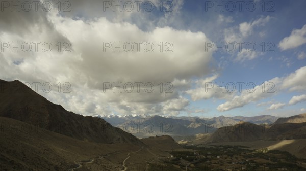 Mountain landscape under a dramatic, cloudy sky with sunny stretches, trekking in Ladakh, Himalayas, India