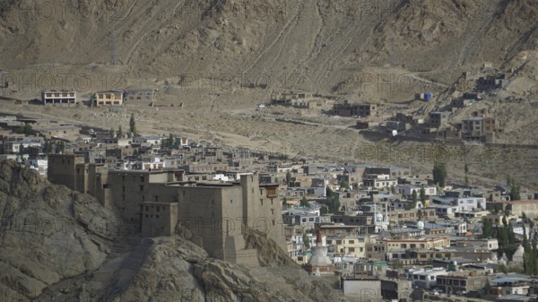 View of the Leh Palace from a hill with Leh in the background in a desert-like environment with traditional buildings, trekking in Ladakh, Himalayas, India