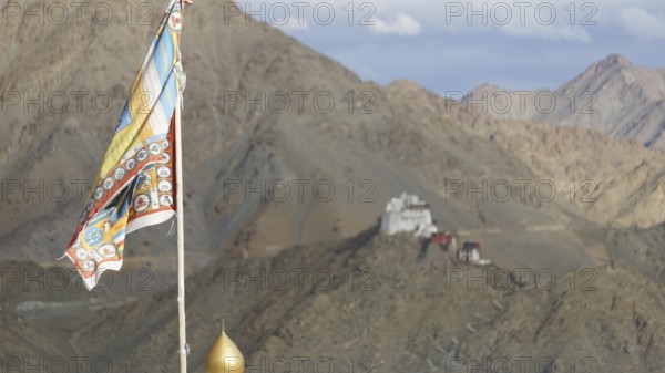 Colourful Buddhist flag against a mountain backdrop with Namgyal Tsemo monastery in the distance, Leh, trekking in Ladakh, Himalayas, India
