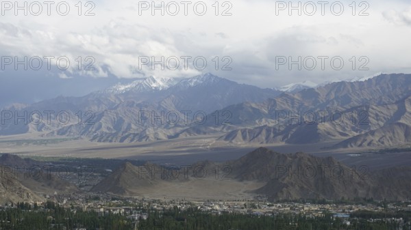 Wide mountain landscape with cloudy sky and distant snow-capped peaks, trekking in Ladakh, Himalayas, India