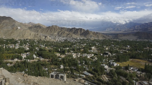 View from above of a city surrounded by mountains under a wide sky, trekking in Ladakh, Himalayas, India