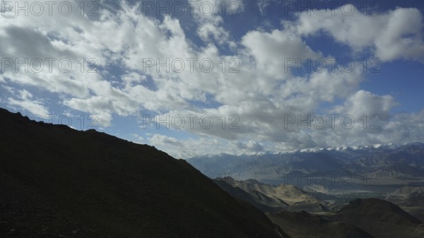 View of dark shades of mountains under a sky full of clouds, trekking in Ladakh, Himalayas, India