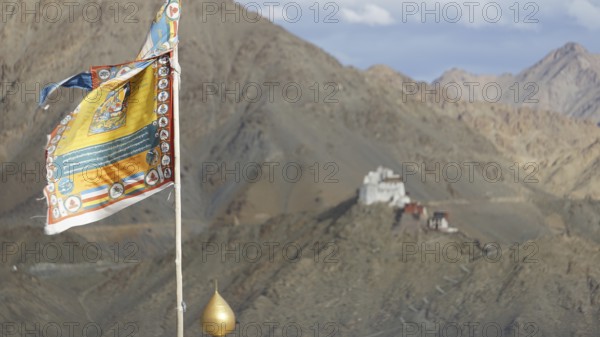 Colourful Buddhist flag with Namgyal Tsemo Buddhist monastery surrounded by mountains and sky, Leh, trekking in Ladakh, Himalayas, India