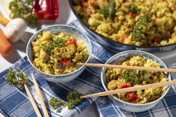 Dishes of fried rice and chopsticks next to the pan, decorated with parsley