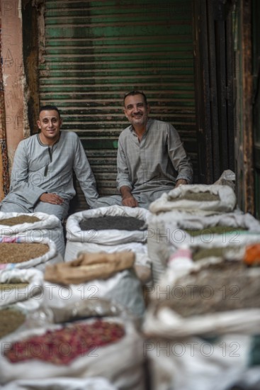 Cairo, Egypt. July 1st 2024 Two Egyptian men sit amongst sacks of spices in the Cairo spice market near the busy Khan el Khalili shopping bazaar, popular with locals and tourists. Egypt