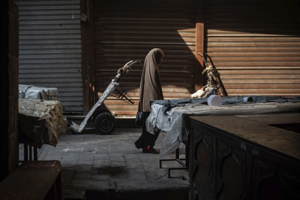 Cairo, Egypt. July 1st 2024 An Egyptian Muslim woman walks along the cobbled streets of a closed market near the Al Ahzar Mosque in Midan Hussein, Islamic Cairo, Egypt