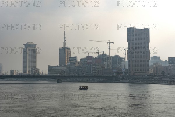 Cairo, Egypt. July 1st 2024 Building and construction cranes of the Cairo city skyline seen through hazy polluted air beside the River Nile, Egypt