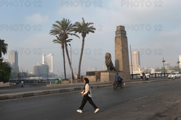 Cairo, Egypt. July 1st 2024 A young muslim Egyptian woman crosses Qasr El Nile Bridge in the early morning, Downtown Cairo, Egypt