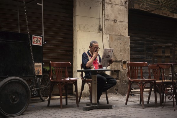 Cairo, Egypt. June 14th 2024 An Egyptian man smokes, drinks tea and reads a newspaper in local café in Downtown Cairo, Egypt
