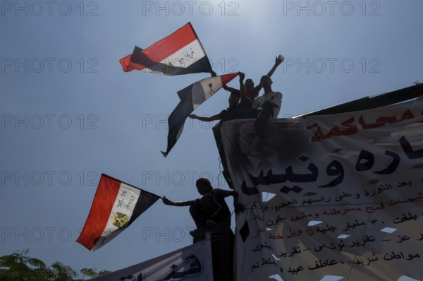 Cairo, Egypt. July 15th 2011 Anti government protestors with banners and flags silhouetted against the sky, Tahrir square, Cairo, Egypt. A young Egyptian girl shows the victory sign during a protest in Tahrir Square after the Egyptian revolution on January 25th