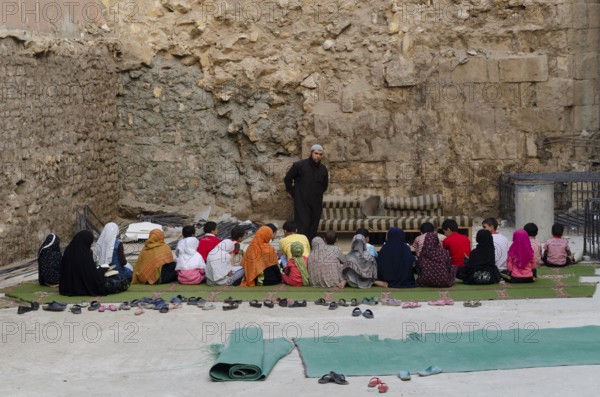Cairo, Egypt. 21st October 2011 An open air school class and Muslim teacher giving lessons to children sitting on the floor in the poor Al Darb al Ahmar neihborhood of Islamic Cairo