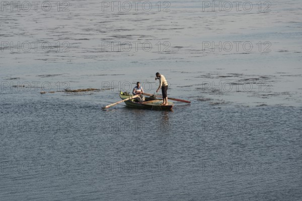 Qanater, Nile Delta. Egypt. December 18th 2022 Egyptian fishermen fishing from a small boat on the River Nile at the Delta Barrages where the Nile River divides into the Damietta and Western Rosetta branches