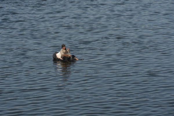 Qanater, Nile Delta. Egypt. December 18th 2022 An Egyptian man fishing from a makeshift inflatable on the River Nile at the Delta Barrages where the Nile River divides into the Damietta and Western Rosetta branches