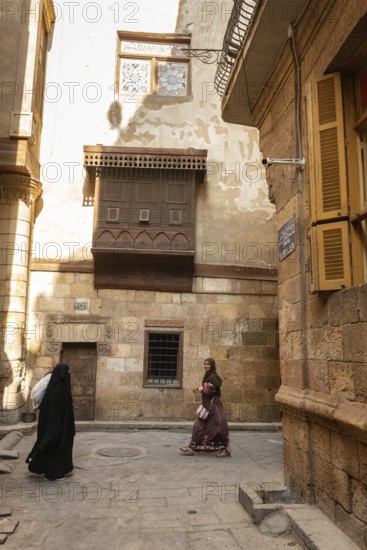 Cairo, Egypt. December 7th 2022 People walk by traditional Arabic Islamic architecture Mashrabiya window of restored building on Darb al Asfar, al Muiz Street, Khan el Khalili bazaar, Islamic Cairo, Egypt