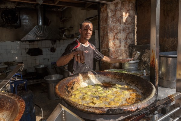 Cairo, Egypt. November 26th 2022 An Egyptian man deep frying Falafel, a chickpea and herb filled snack popular in Egypt and all over the Middle East at his shop in the Islamic Quarter of Cairo, Egypt