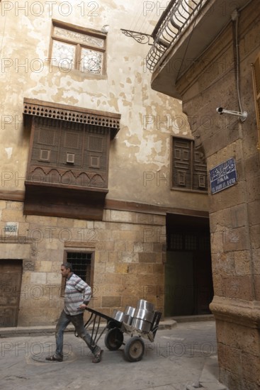 Cairo, Egypt. December 7th 2022 People walk by traditional Arabic Islamic architecture Mashrabiya window of restored building on Darb al Asfar, al Muiz Street, Khan el Khalili bazaar, Islamic Cairo, Egypt