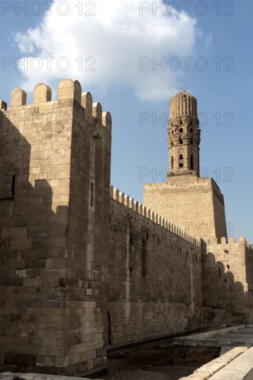 Cairo, Egypt, November 26th 2022 Minaret of the Al Hakim Mosque with the fortified defensive Northern walls of Islamic Cairo, near Bab El Futuh one of the ancient gates of the historical Egyptian city of Cairo, Egypt