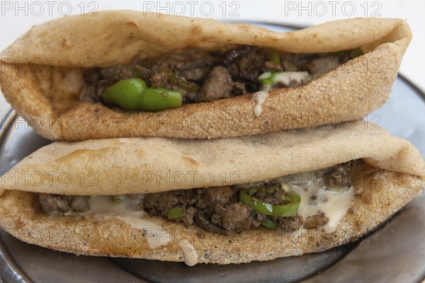 A plate of tasty fried liver and spicy green pepper sandwiches, one of the most popular street food snacks in Egypt being prepared at a Cairo street stall