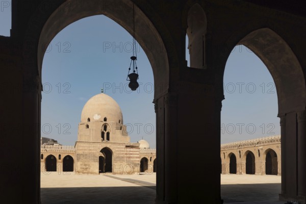 Silhouetted arches of the interior architecture and courtyard showing the dome of Ibn Tulin Mosque in Cairo, one of the oldest mosques in Egypt